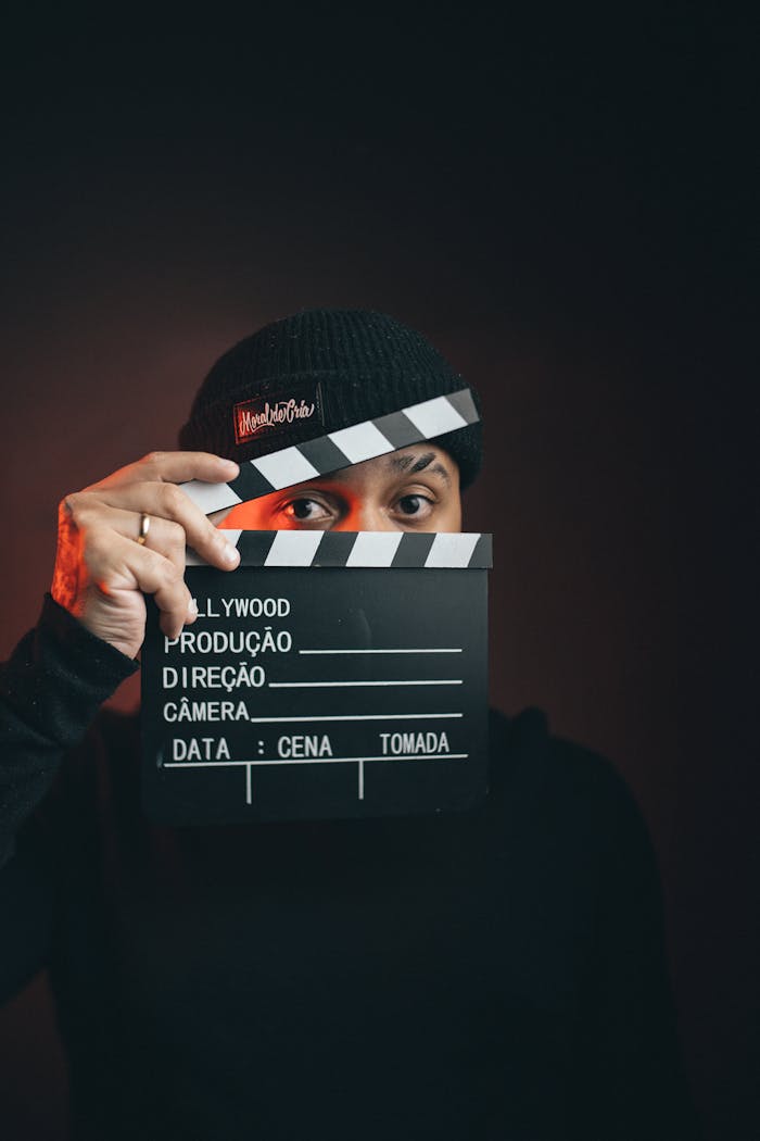 about-03 Portrait of a man holding a clapperboard with a dramatic dark background.
